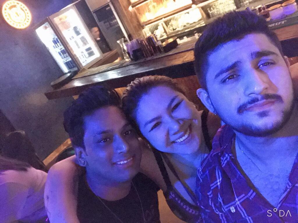 AI caption: a group of people taking a selfie at a bar, portrait