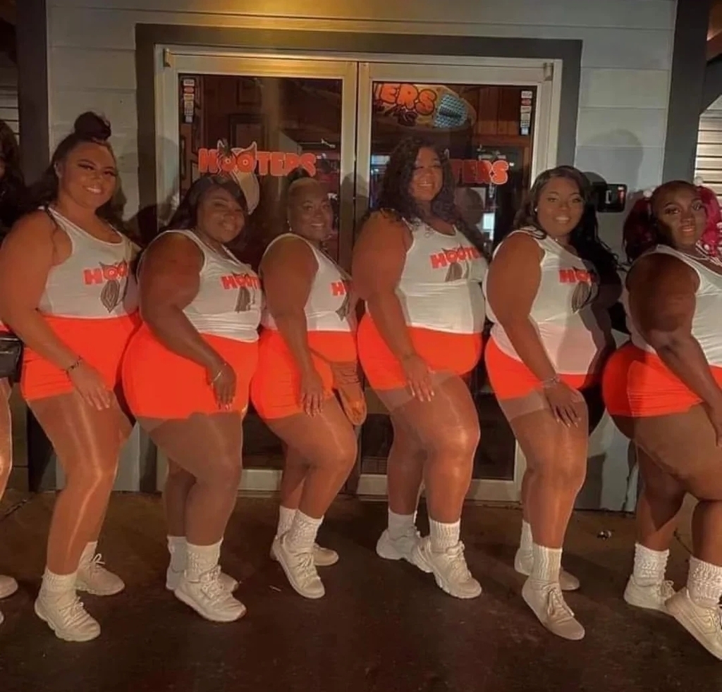 AI caption: a group of women in orange shorts posing for a photo, portrait