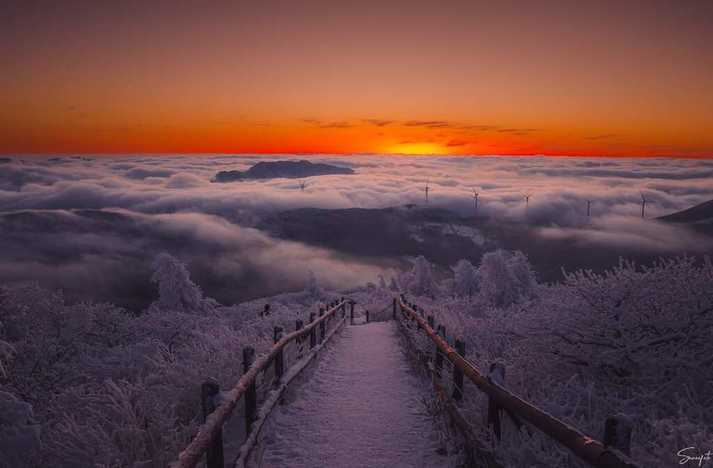 AI caption: the sun rises over a frozen mountain with clouds, abstract
