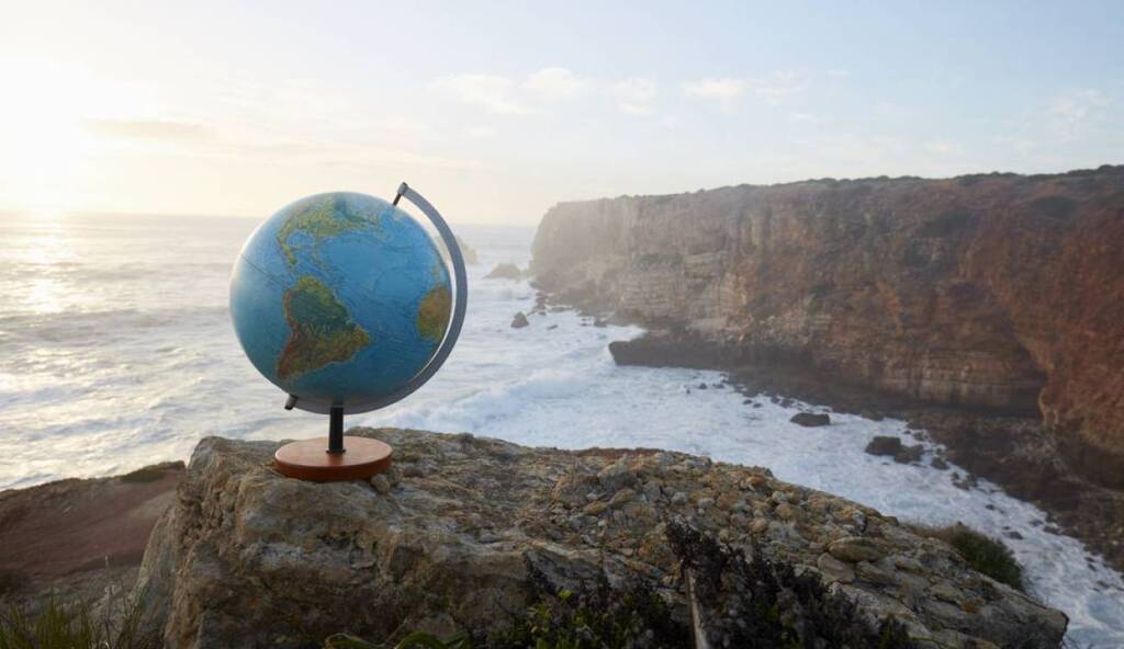 AI caption: a globe sitting on top of a rock near the ocean, adobe photoshop