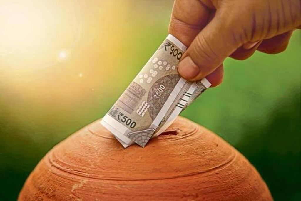 AI caption: a person is putting money into a clay pot, hand holding a banknote