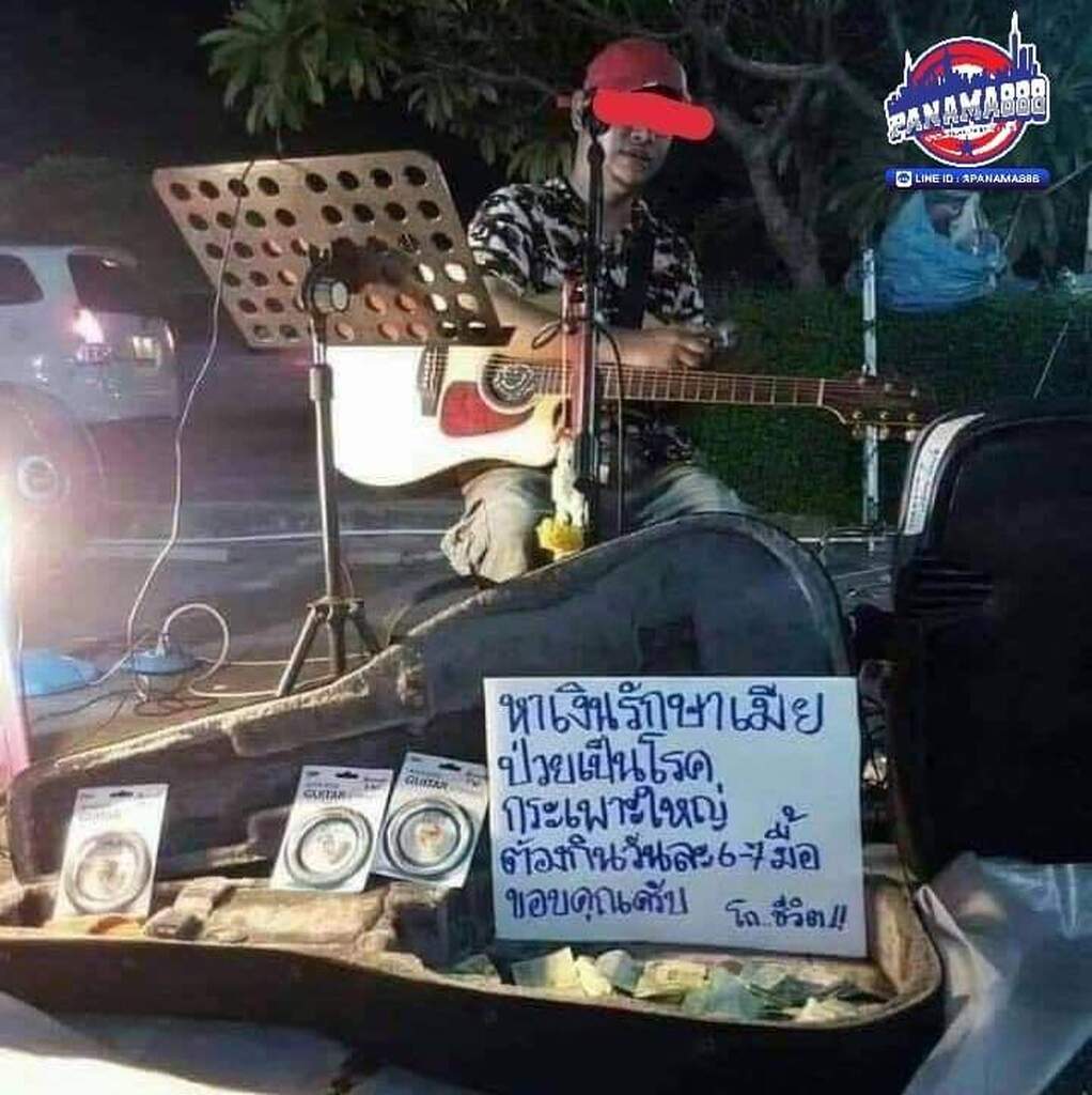 AI caption: a man playing guitar on a street in thailand, black and white