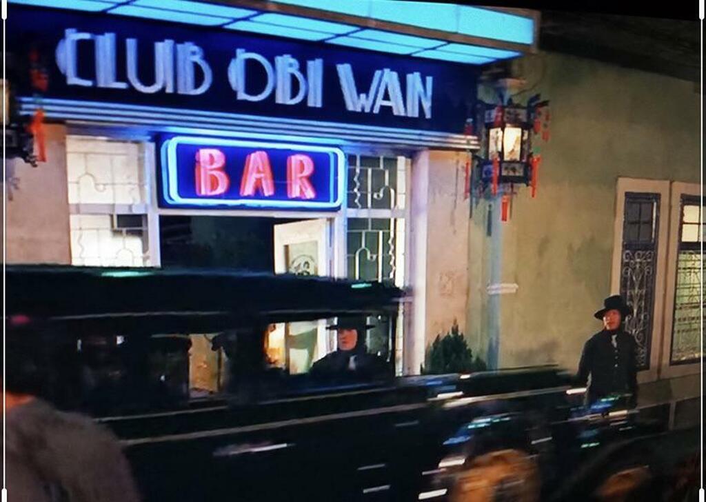 AI caption: a picture of a star wars statue and a r2d2, a comic book style a man in a car is standing outside of a bar