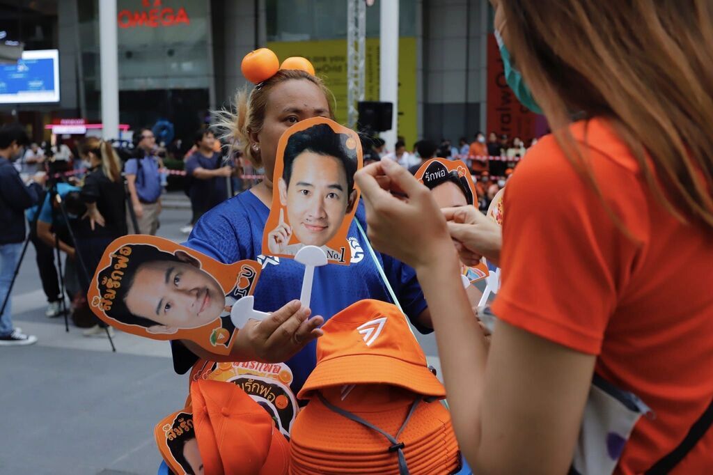 AI caption: a crowd of people sitting on the ground in front of a building, portrait a crowd of people with orange umbrellas on a street, the image is a satire of the muslim community, portrait a group of people are holding up pictures of people, the woman is wearing a hat with a picture of a man