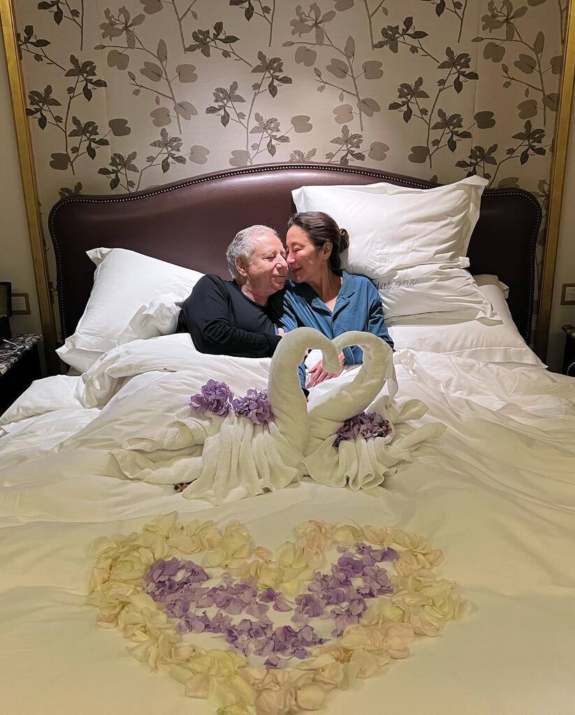 AI caption: a woman holding a framed poster of love never dies, portrait a couple laying in bed with swans on the bed